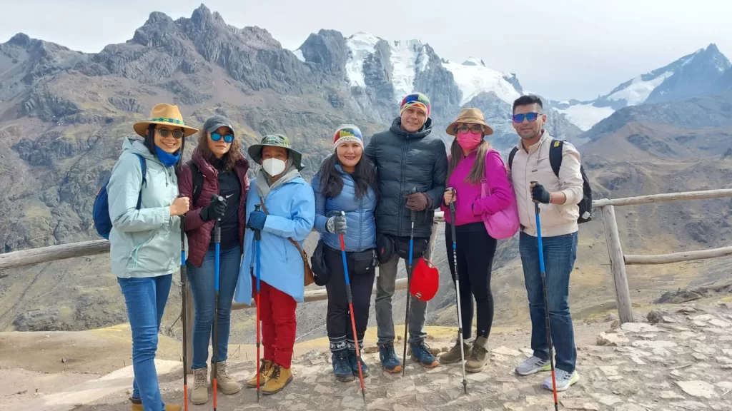 Tourists posing in front of the snow-capped Huamantay Mountains.